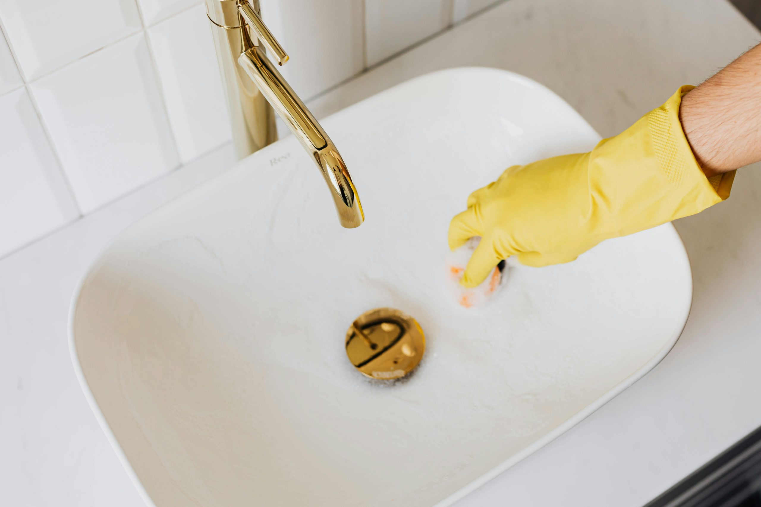 Cleaner scrubbing office bathroom sink during professional cleaning service in Logan
